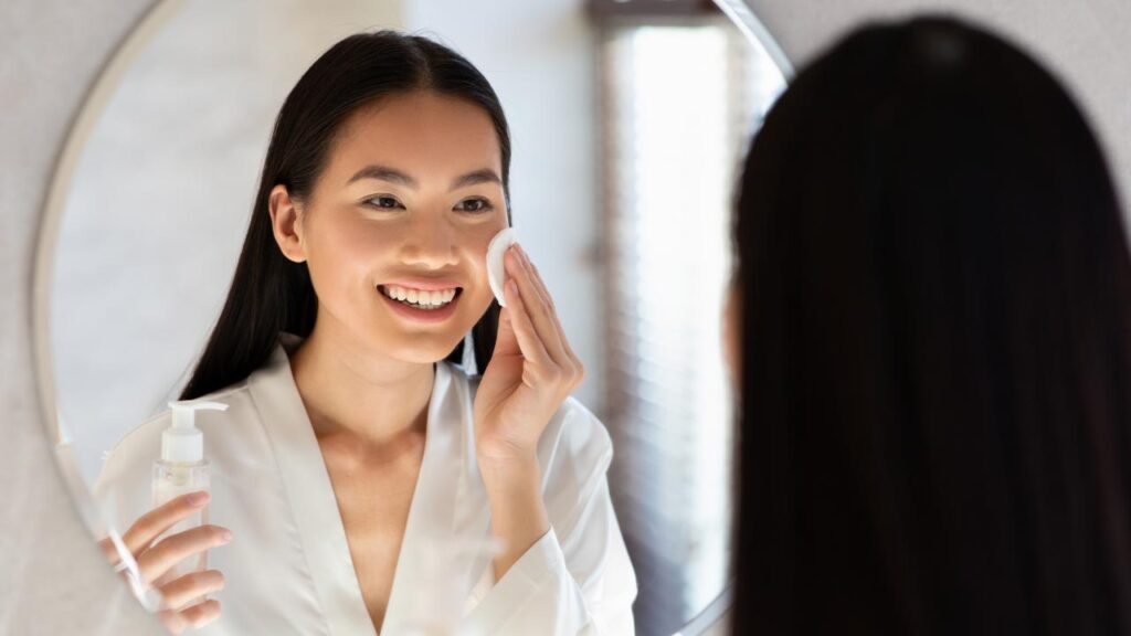 A woman with even skin tone applying toner to face