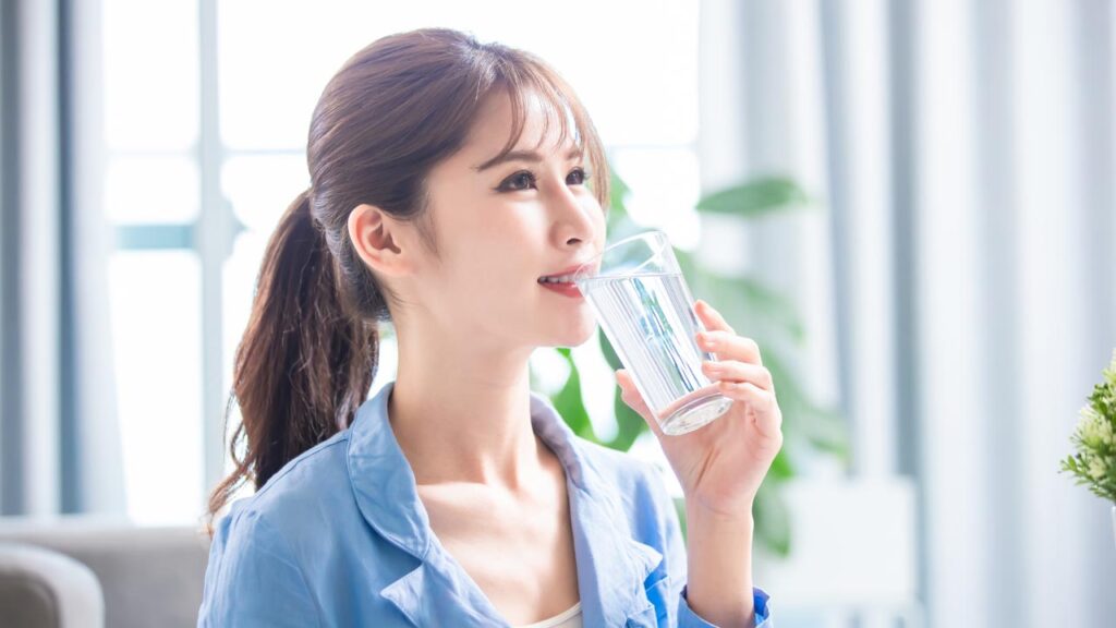 A woman with healthy looking skin drinking water