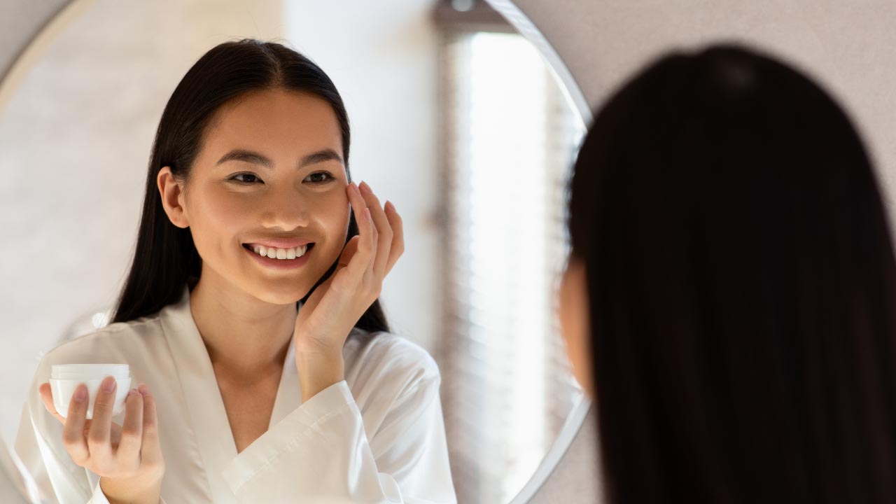 a smiling woman applying a cream product